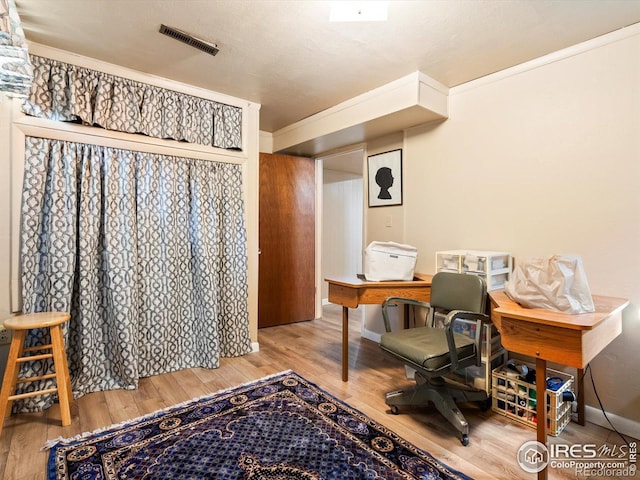 office space with wood finished floors, ornamental molding, baseboards, and visible vents
