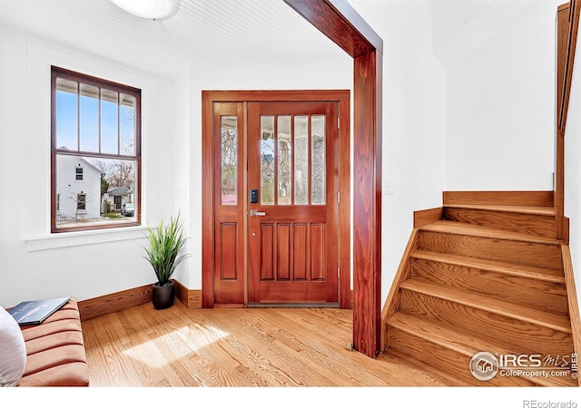 entrance foyer with stairs, wood finished floors, and baseboards
