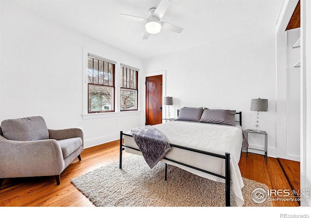 bedroom with a ceiling fan, baseboards, and wood finished floors
