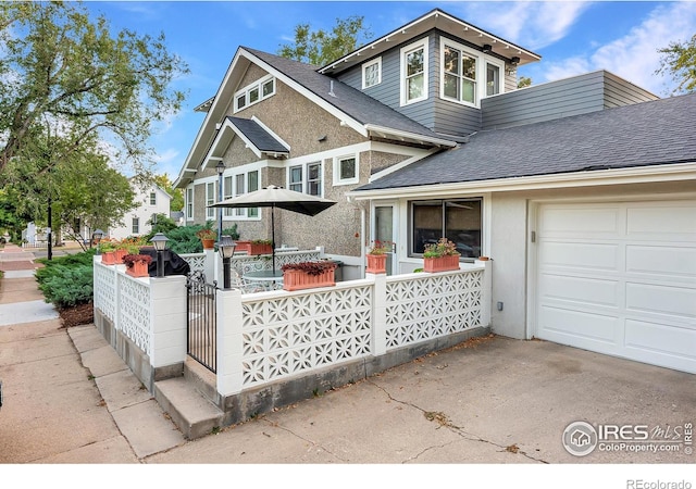 view of front of home with stucco siding, a shingled roof, and an attached garage