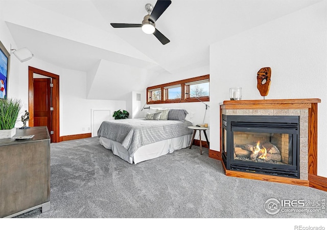 bedroom featuring carpet, lofted ceiling, a glass covered fireplace, and baseboards