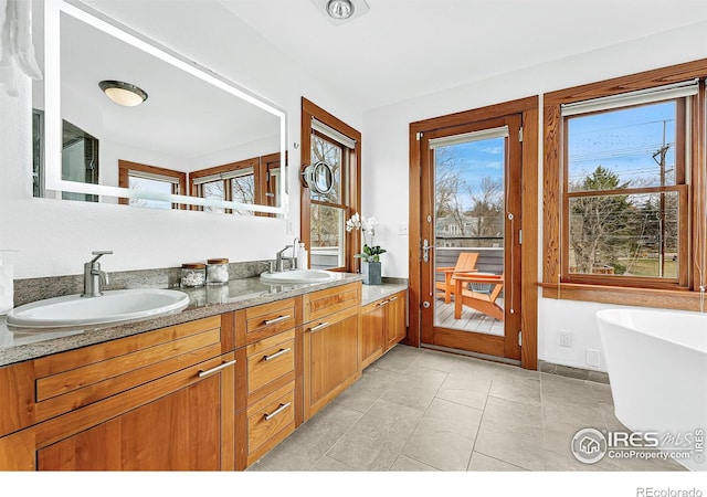 full bath with double vanity, a sink, and a freestanding tub