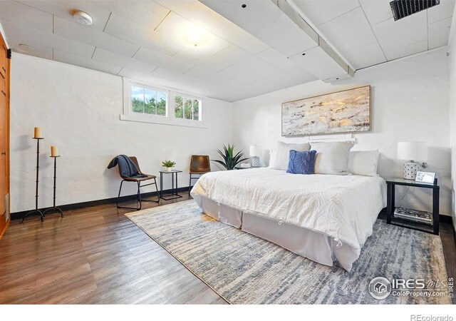 bedroom featuring baseboards, visible vents, and wood finished floors