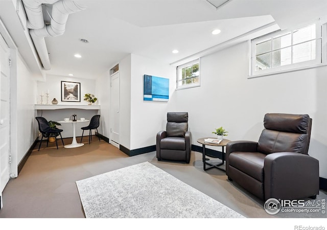 living area featuring finished concrete flooring, baseboards, and recessed lighting