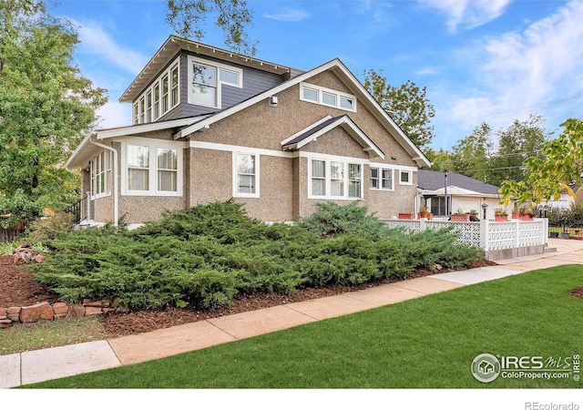 view of front of home with a front lawn, stucco siding, and fence