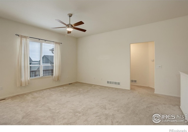 unfurnished room with light carpet, a ceiling fan, visible vents, and baseboards