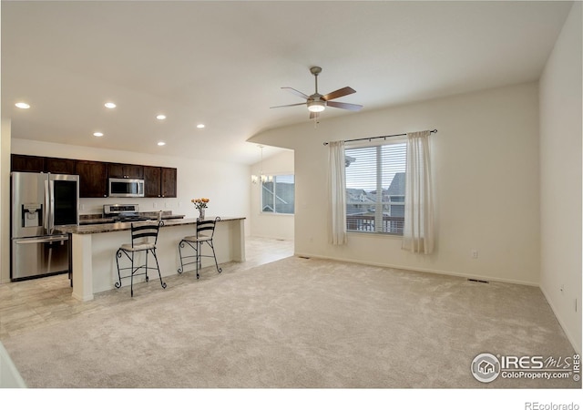 kitchen featuring dark brown cabinets, recessed lighting, a kitchen bar, ceiling fan with notable chandelier, and appliances with stainless steel finishes
