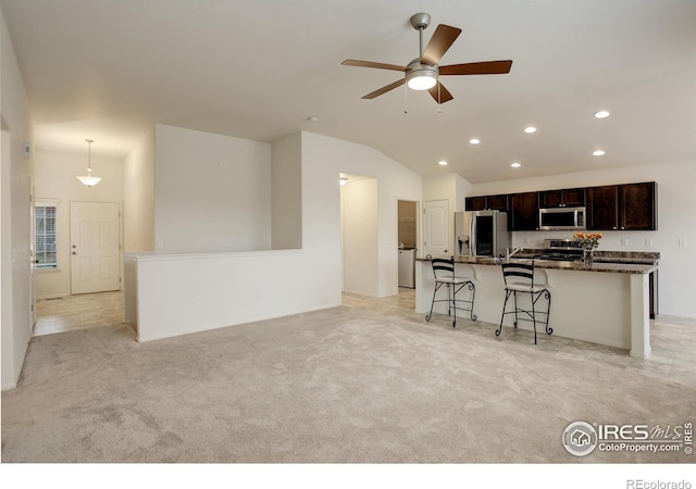 kitchen featuring stainless steel appliances, vaulted ceiling, recessed lighting, a ceiling fan, and a breakfast bar area