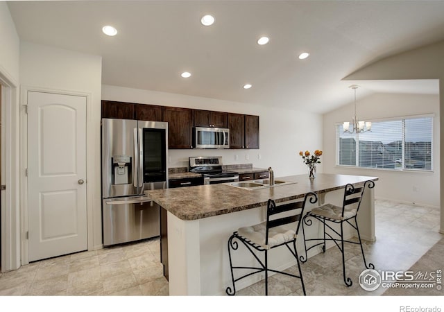 kitchen featuring dark countertops, a kitchen breakfast bar, a sink, dark brown cabinetry, and stainless steel appliances