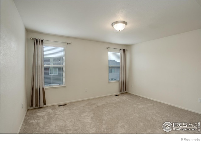 carpeted empty room featuring baseboards and visible vents