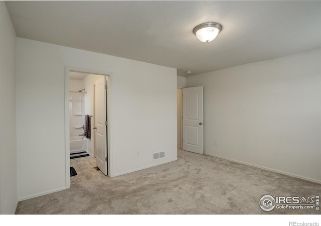unfurnished bedroom with carpet floors, visible vents, baseboards, and ensuite bathroom