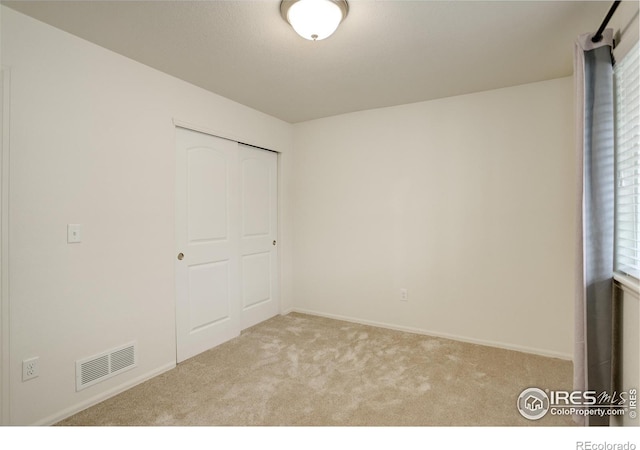 unfurnished bedroom featuring baseboards, a closet, visible vents, and carpet