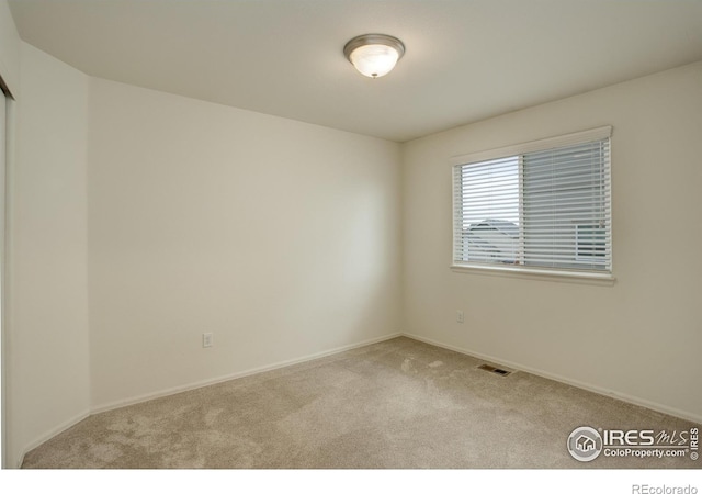 carpeted empty room featuring baseboards and visible vents