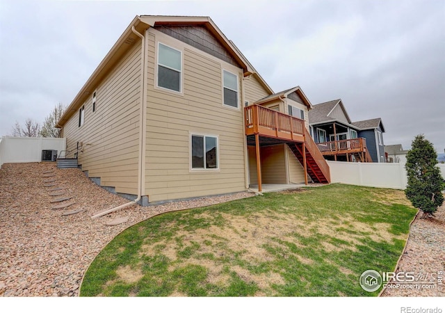 rear view of property featuring stairway, fence, a yard, central air condition unit, and a deck