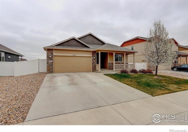 view of front of property with concrete driveway, covered porch, fence, a front yard, and a garage