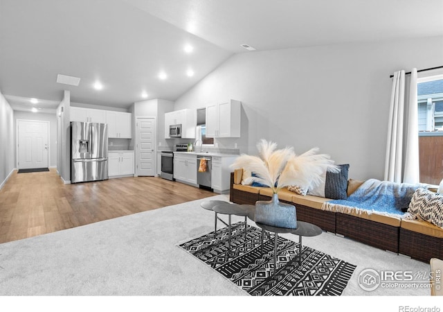 702 S Fulton Ave, Fort Lupton, CO 80621 - living room with light colored carpet, vaulted ceiling, recessed lighting, and light wood-style flooring