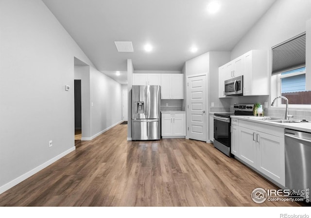 702 S Fulton Ave, Fort Lupton, CO 80621 - kitchen featuring appliances with stainless steel finishes, white cabinetry, wood finished floors, light countertops, and recessed lighting