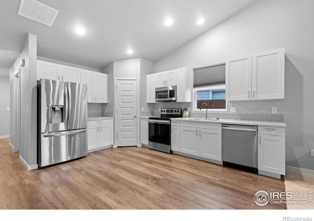 702 S Fulton Ave, Fort Lupton, CO 80621 - kitchen featuring appliances with stainless steel finishes, white cabinets, light countertops, light wood-type flooring, and vaulted ceiling
