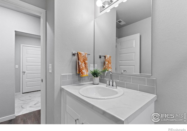 702 S Fulton Ave, Fort Lupton, CO 80621 - bathroom featuring vanity, marble look tile flooring, and tasteful backsplash