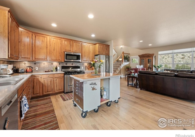 229 Rustic Rd, Bellvue, CO 80512 - kitchen with stainless steel appliances, light wood-style flooring, open floor plan, light countertops, and backsplash