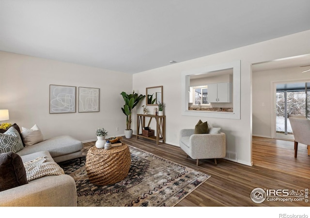 living area featuring baseboards, visible vents, and wood finished floors