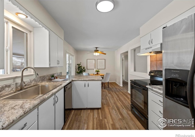 kitchen featuring stainless steel fridge, black / electric stove, under cabinet range hood, a sink, and dishwashing machine