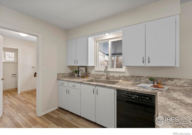 kitchen featuring black dishwasher, a sink, light wood-style flooring, and a wealth of natural light