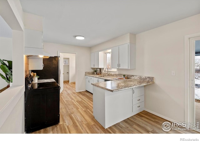 kitchen with white cabinetry, light countertops, a sink, range with electric stovetop, and a peninsula
