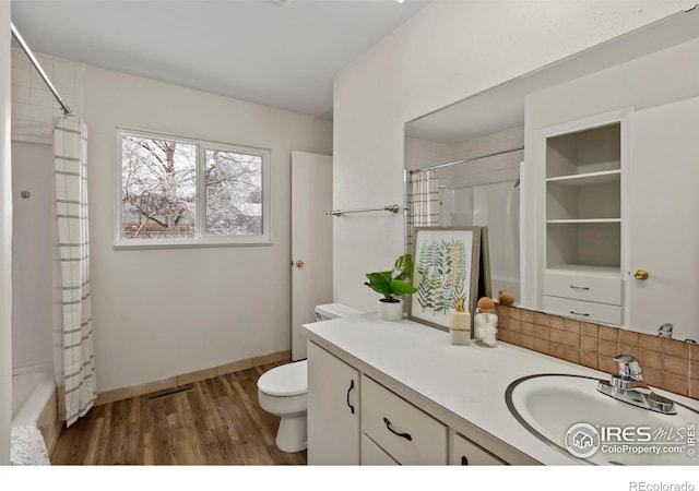 bathroom with vanity, toilet, a shower with shower curtain, visible vents, and wood finished floors