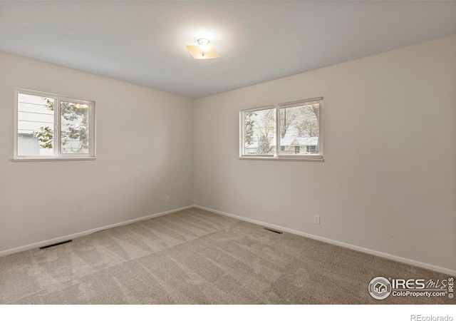 carpeted empty room featuring baseboards and visible vents