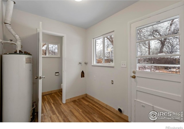 doorway featuring baseboards, gas water heater, and light wood-style floors