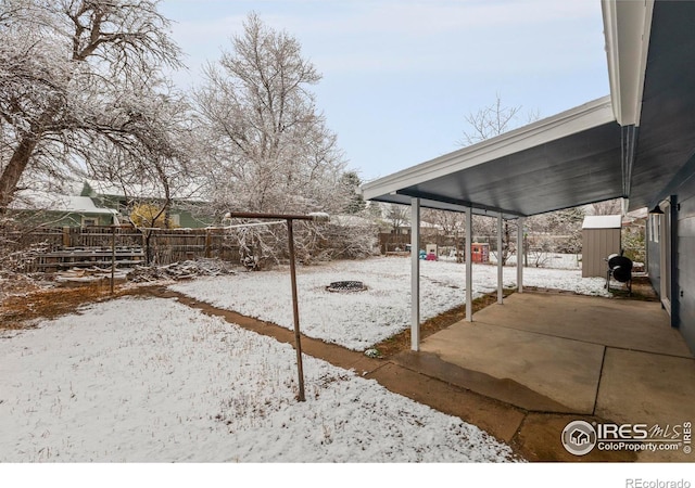 yard layered in snow with fence and a patio area