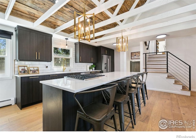2017 Harmony Dr, Fort Collins, CO 80525 - kitchen featuring light wood-type flooring, stainless steel appliances, a chandelier, backsplash, and beam ceiling