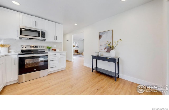 kitchen with light wood-type flooring, light countertops, backsplash, white cabinets, and stainless steel appliances