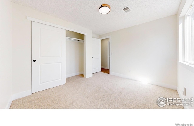 unfurnished bedroom with carpet floors, a closet, visible vents, and a textured ceiling