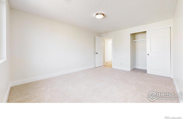 unfurnished bedroom featuring carpet floors, baseboards, a closet, and a textured ceiling