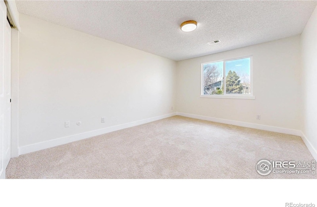 spare room with visible vents, baseboards, light colored carpet, and a textured ceiling