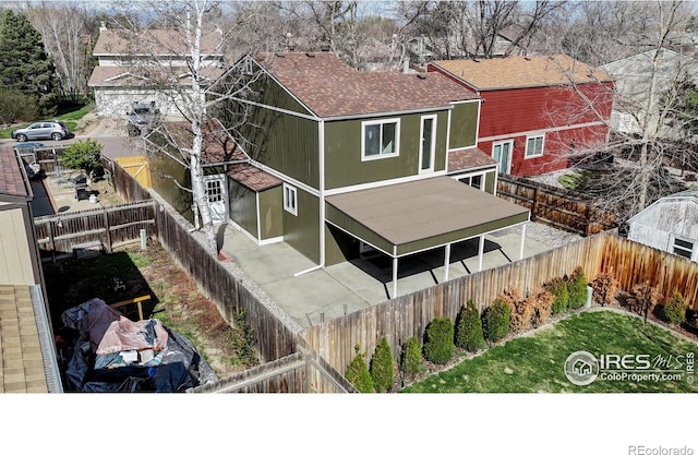 rear view of house featuring a fenced backyard and a shingled roof
