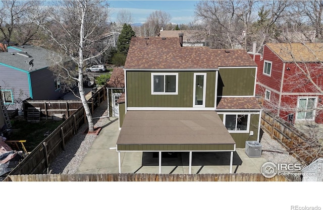 rear view of house with fence private yard, cooling unit, and a shingled roof
