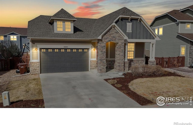craftsman-style home with concrete driveway, stone siding, board and batten siding, covered porch, and roof with shingles
