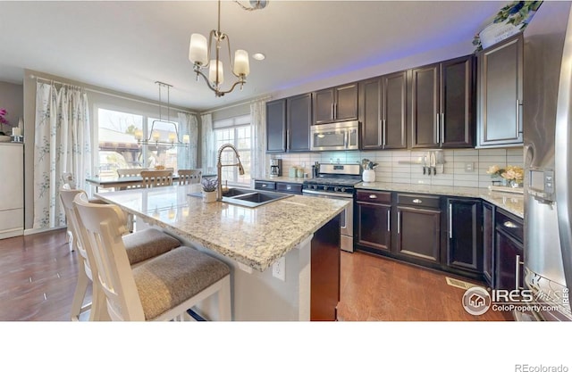 6820 Rainier Rd, Timnath, CO 80547 - kitchen featuring appliances with stainless steel finishes, dark wood-style floors, a chandelier, and tasteful backsplash