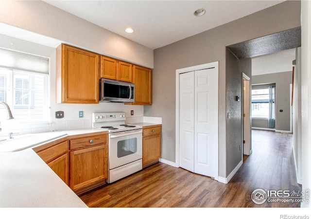 828 Kane Dr Unit 35, Longmont, CO 80501 - kitchen with stainless steel microwave, white range with electric cooktop, wood finished floors, a sink, and light countertops