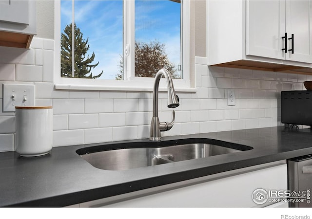 253 Courtney Dr, Loveland, CO 80537 - kitchen featuring tasteful backsplash, a sink, white cabinetry, and dark countertops