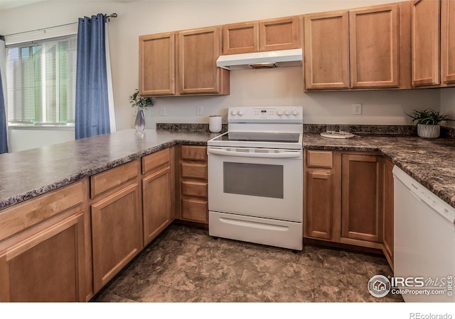 2113 Day Spring Dr, Windsor, CO 80550 - kitchen featuring white appliances, under cabinet range hood, dark countertops, stone finish flooring, and brown cabinetry