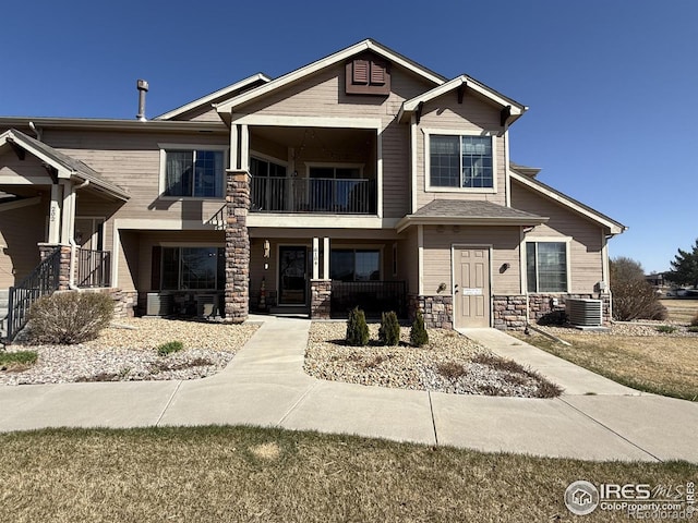 585 Callisto Dr, Loveland, CO 80537 - craftsman-style home featuring central AC unit, a balcony, stone siding, and covered porch