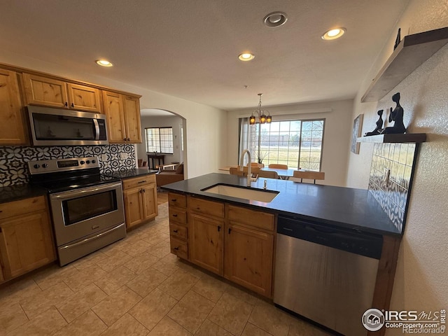585 Callisto Dr, Loveland, CO 80537 - kitchen featuring arched walkways, dark countertops, a sink, and appliances with stainless steel finishes
