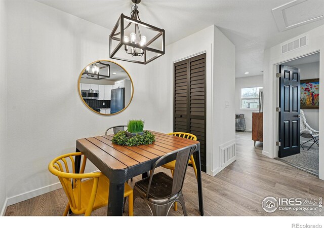 234 Lyons St, Fort Collins, CO 80521 - dining area featuring visible vents, baseboards, an inviting chandelier, and light wood-style floors