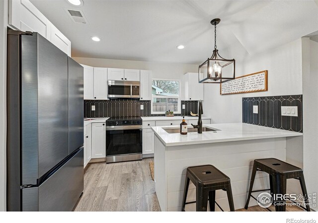 234 Lyons St, Fort Collins, CO 80521 - kitchen with a kitchen bar, a peninsula, visible vents, white cabinets, and appliances with stainless steel finishes