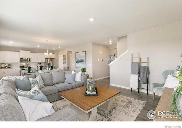 living area featuring dark wood-style flooring, baseboards, recessed lighting, and a notable chandelier