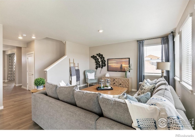 living area with recessed lighting, baseboards, stairs, and wood finished floors